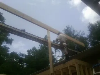 Carpenter setting a ridge beam over a new addition frame — Ice Dam Removal by Roofing Brothers in Holmes