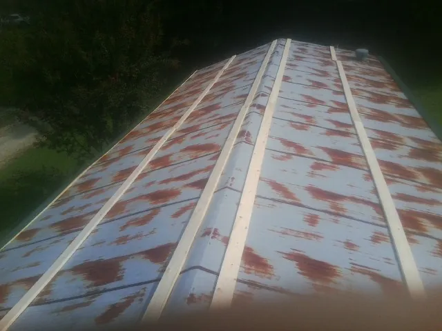 Rusted metal roof panels with new wood purlins before replacement — Storm Damage Roof Repair in Holmes by Roofing Brothers