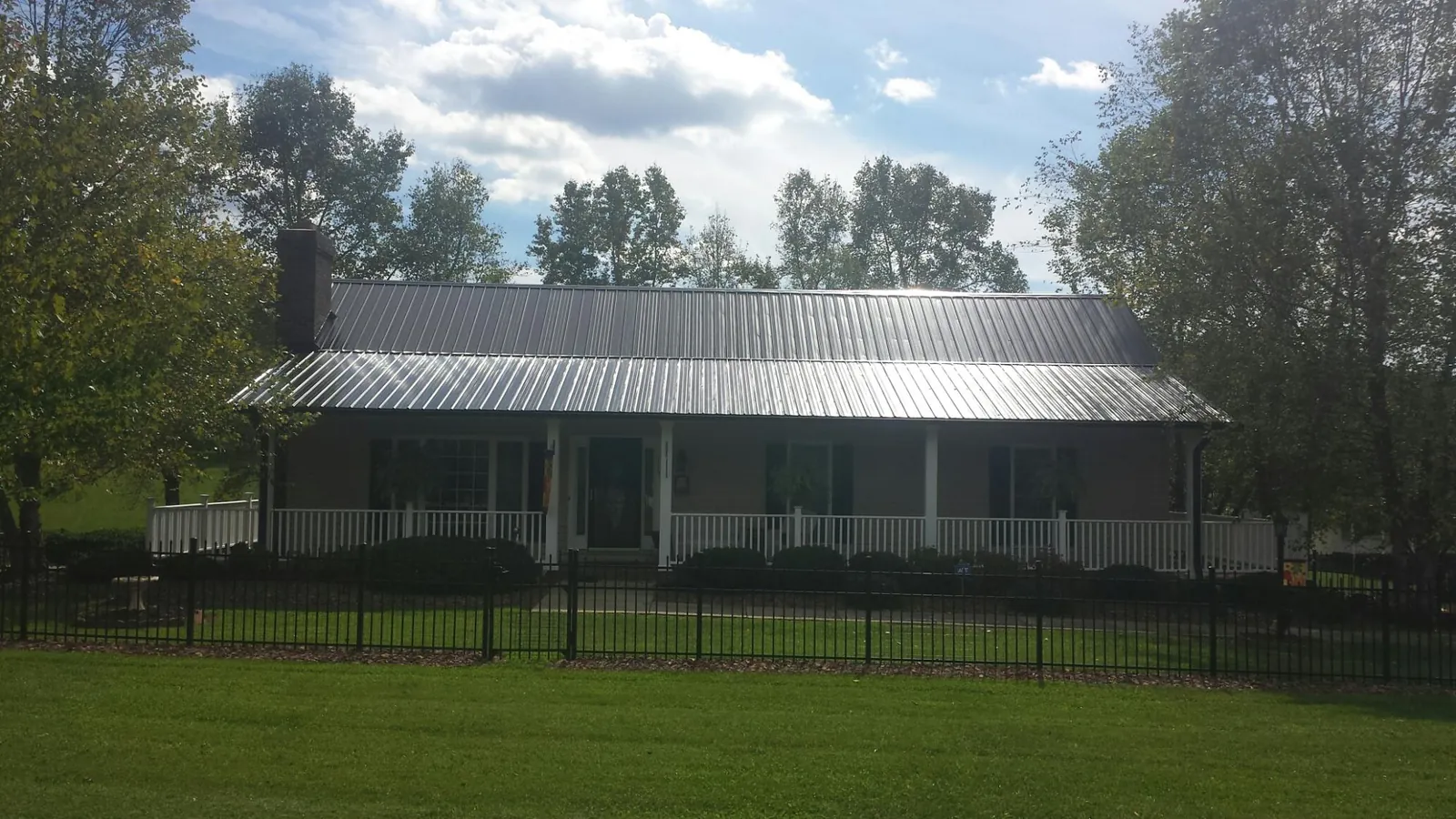 Gray metal roof on a brick ranch with a full width front porch — Gutter Guard Installation work by our crew in Holmes